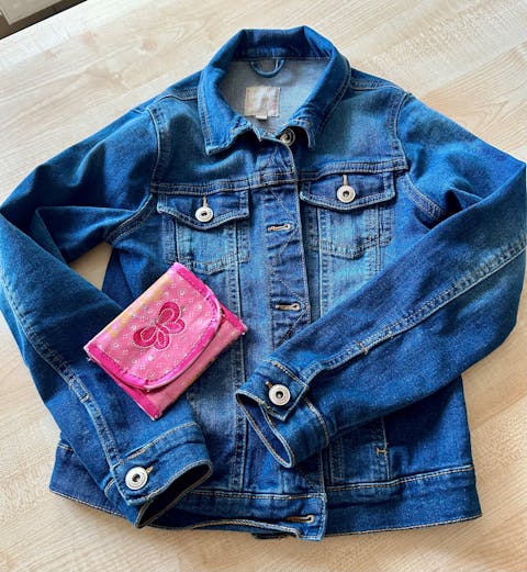 blaue Jeansjacke und pinke Geldbörse